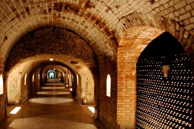 A long brick-vaulted cellar corridor with bottles stacked along the walls