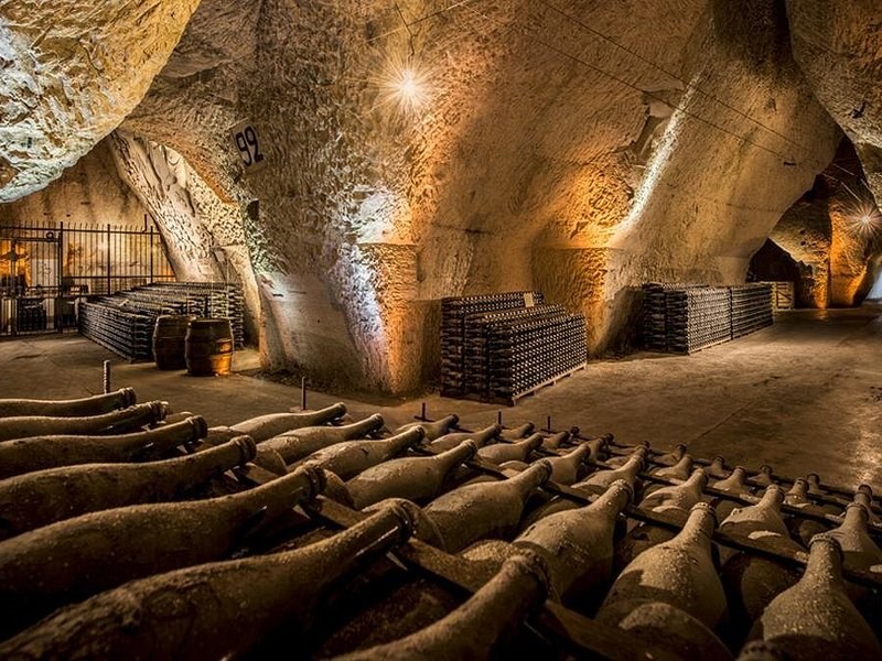 A chalk cellar with bottles laid in rows under its carved walls