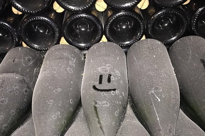 Dusty bottle bottoms in a cellar stack, a smiley face drawn in the dust