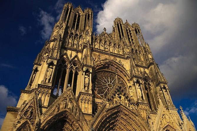 Reims Cathedral's carved west front against a darkening sky